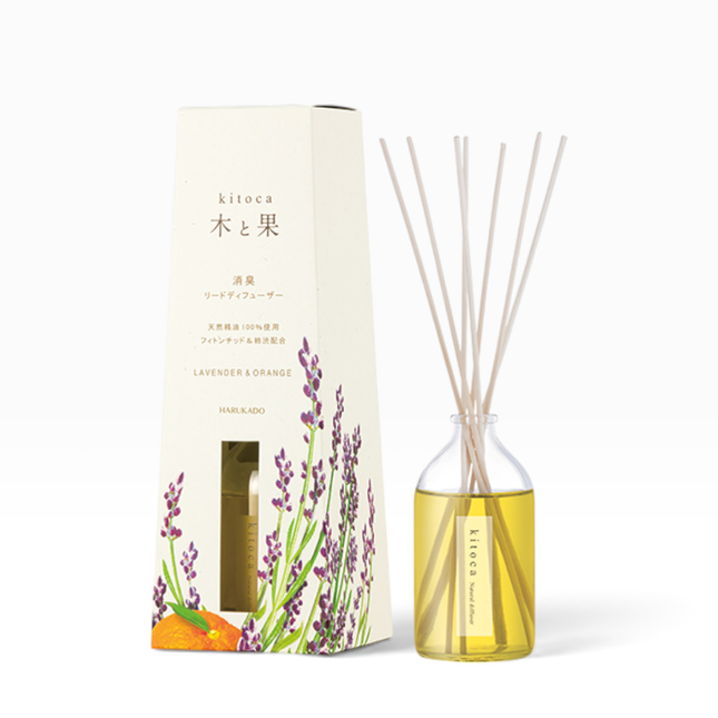 A reed diffuser set with a clear glass bottle filled with yellow liquid and natural reed sticks, shown beside its cream-colored packaging box decorated with lavender and orange illustrations. The brand name 'kitoca' is visible on both the box and the bottle label.