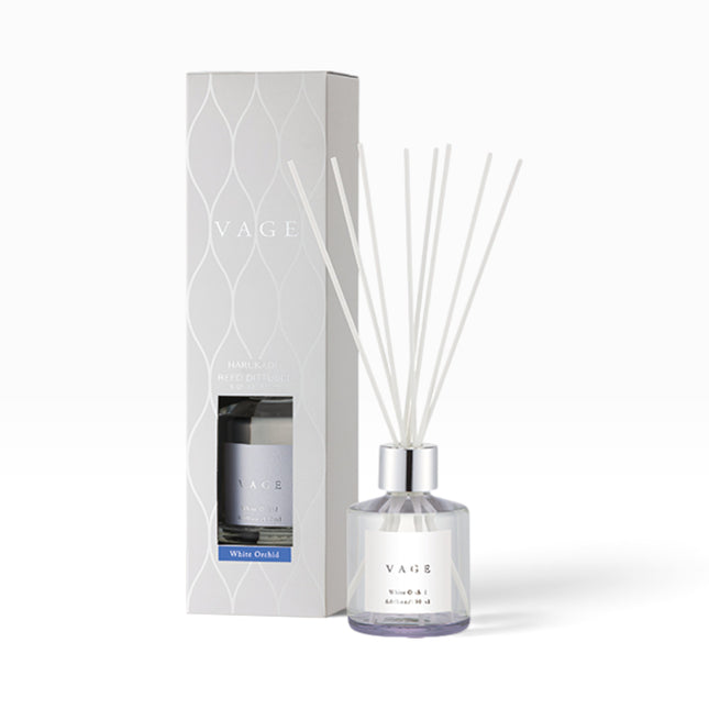 VAGE White Orchid reed diffuser with a clear glass bottle, silver cap, white reeds, and a matching white patterned box on a white background.