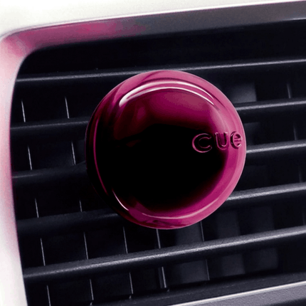Pink 'CUE' air freshener on a car vent