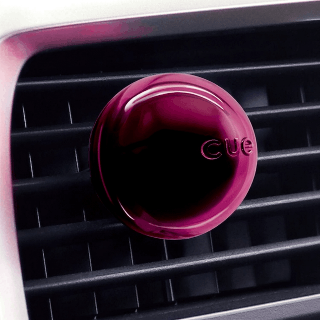 Pink 'CUE' air freshener on a car vent