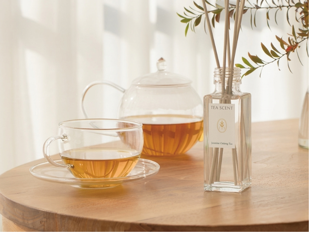 Tea set with a teapot, glass cup, and diffuser on a wooden table.