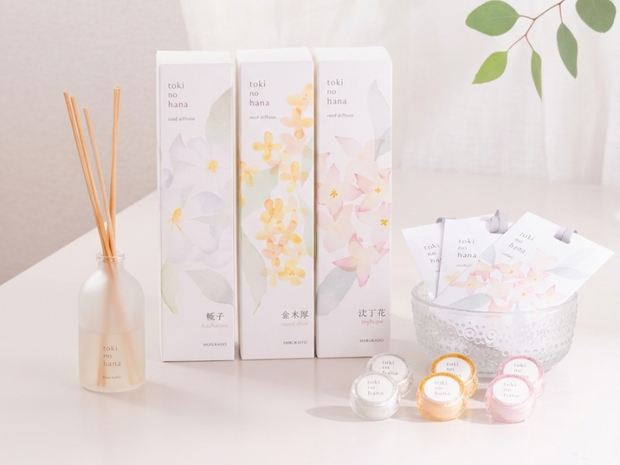 Set of white boxes with floral designs on a light surface with candles and a plant.