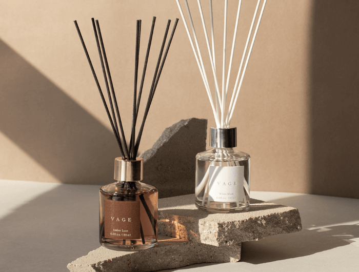 Two diffusers with reeds on a stone surface against a beige background